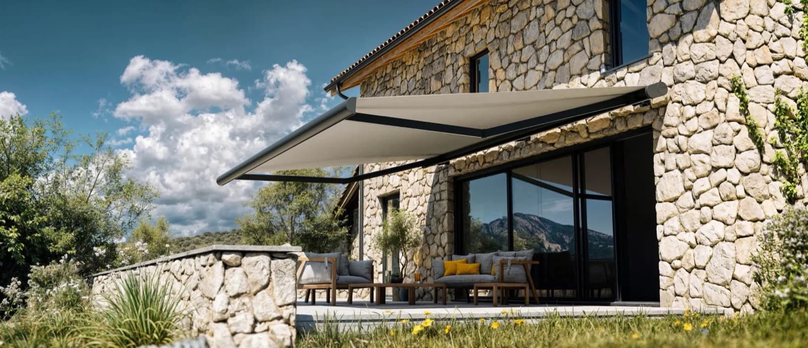 Store banne déployé au-dessus de la terrasse d'une maison en pierre
