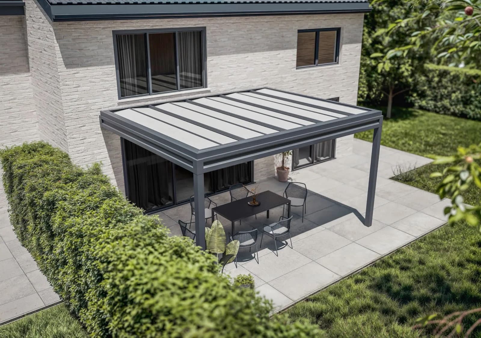 Pergola bioclimatique adossée à la façade d’une maison, au-dessus de la terrasse